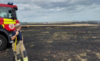 A firefighter look out over the burnt grassland