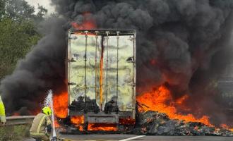 Firefighters setting up a hose to spray water on a burning lorry