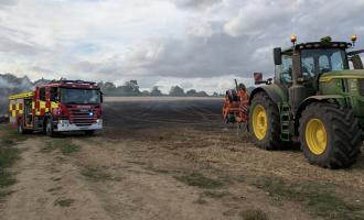 A fire engine and a tractor at a field fire where crews worked with a local farmer