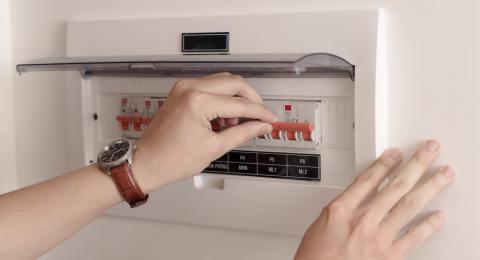 Women's hands resetting a fuse box on the wall