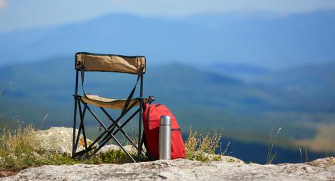 Camping chair on a hill with a backpack and a flask