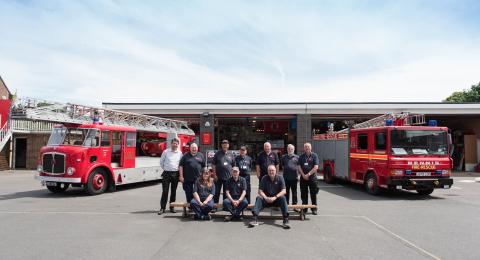 Two fire engines parked in front of the museum with two rows of volunteers lined up.