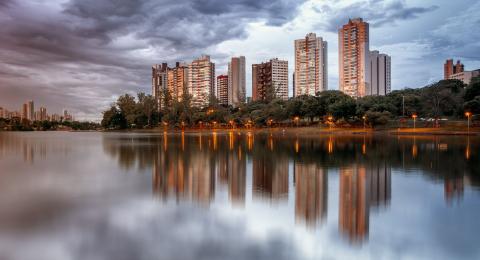 Several tall buildings sitting on the riverside at dusk