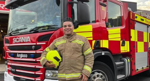 Dominic Daniel, on-call firefighter, stands in front of a fire engine.