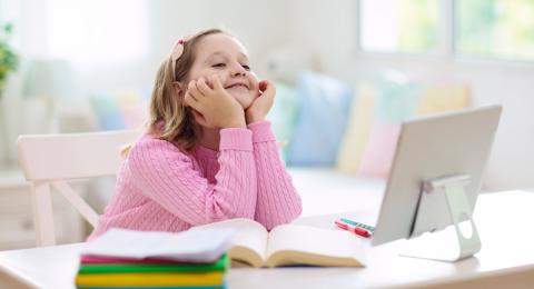 Girl, aged 9, wearing pink jumper sat at a laptop