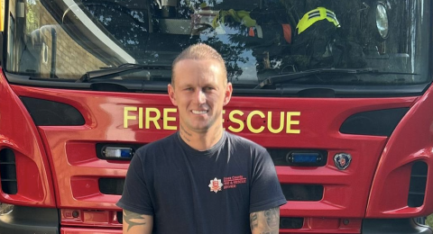 Firefighter Luke Oliver standing in front of a fire engine
