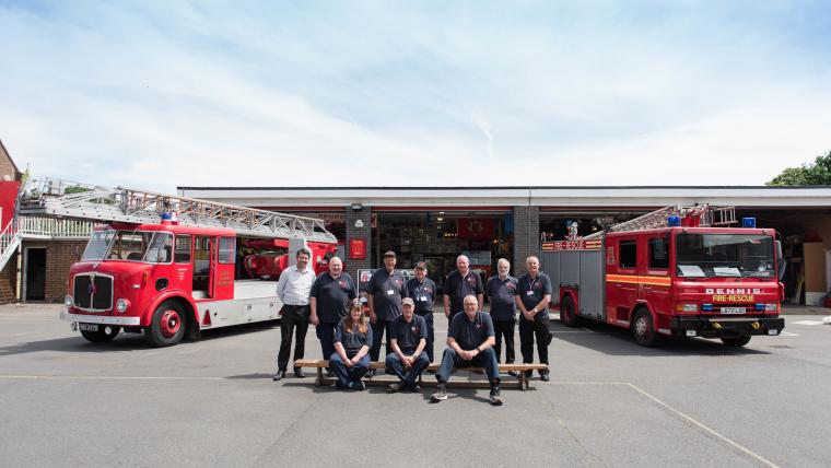 Two fire engines parked in front of the museum with two rows of volunteers lined up.