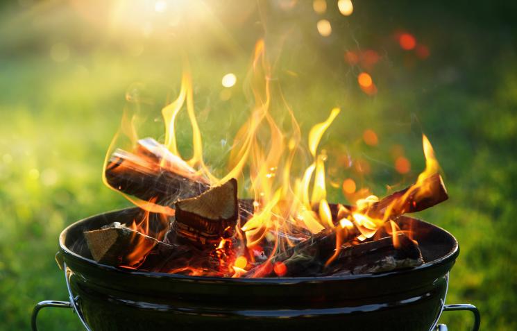 Charcoal barbecue set on grassy area with golden sun beams in the background
