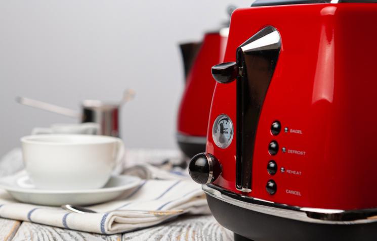 Red kettle and toaster on white wooden surface