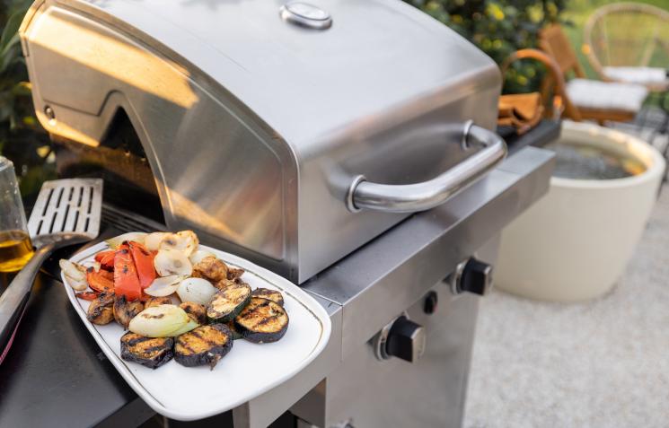 Stainless steel gas barbecue with a plate of barbecued food