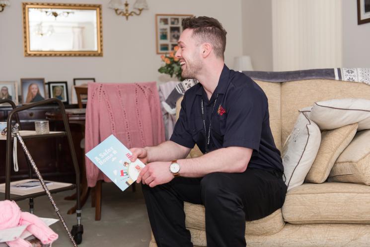 A home fire safety office sits on sofa in living room, offering safety advice