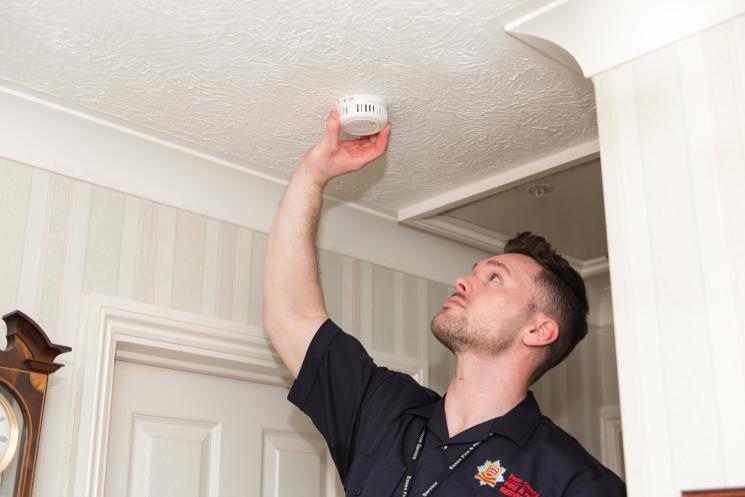 Fire Safety Officer fitting smoke alarm on ceiling