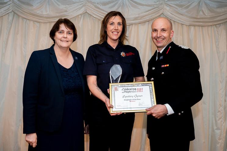 Photo of Jane Gardner, Deputy PFCC, Firefighter Lyndsey Gymer and Rick Hylton our Chief Fire Officer on stage at our Celebrating People Awards. Lyndsey is in the centre holding her winner's certificate and trophy.