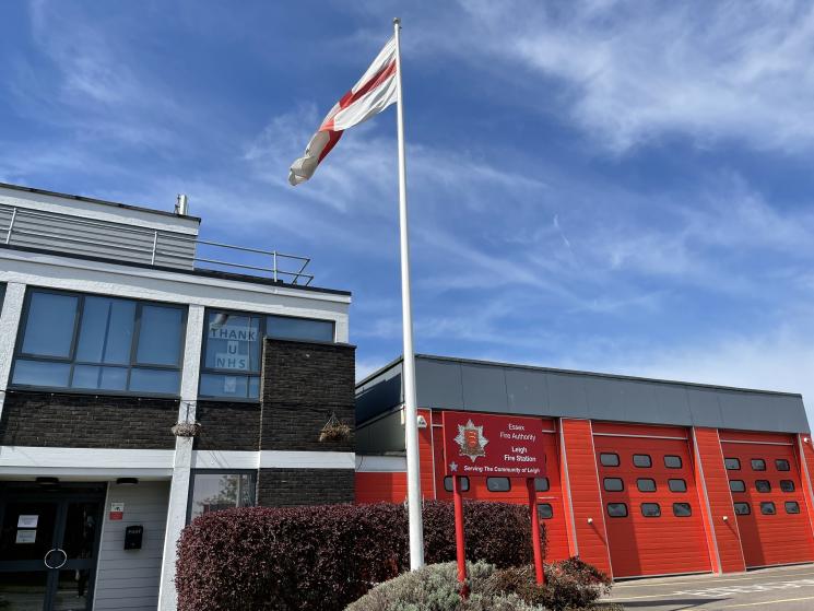 Fire Station building with three red shutter doors and a flag pole outside.