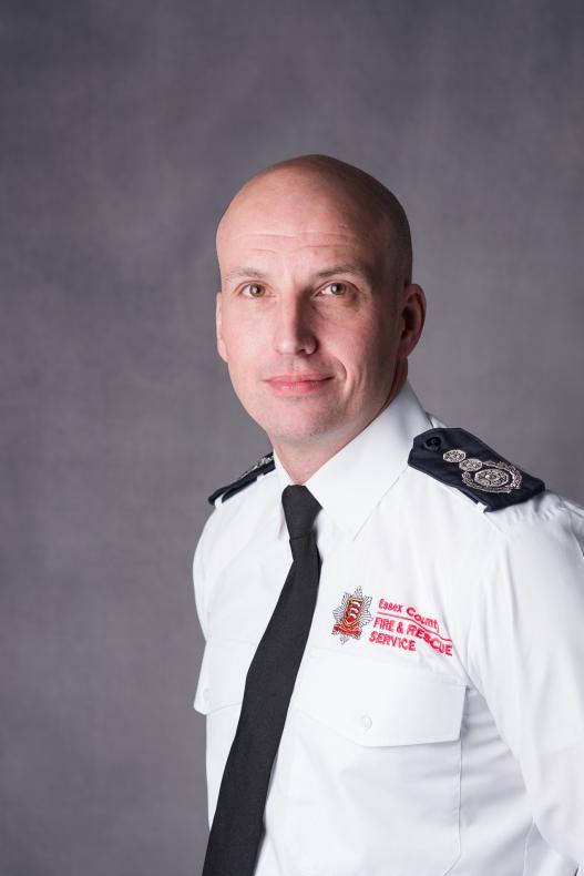 A portrait head and shoulders photograph of our Chief Fire Officer Rick Hylton. He is wearing a white shirt and black tie.