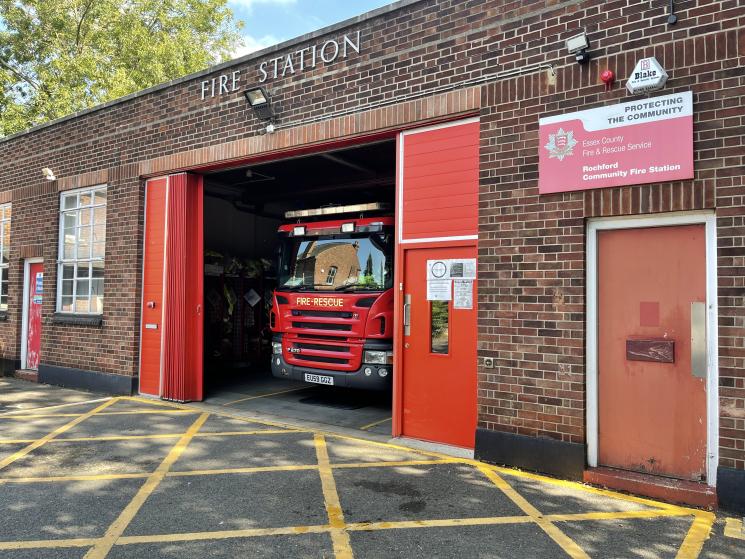 Small brick fire station building with one red shutter door. Fire engine visible inside.