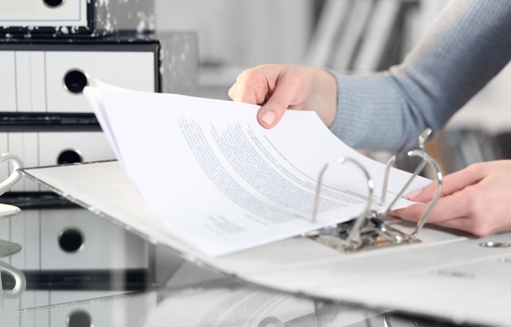 Two hands putting paper into a folder