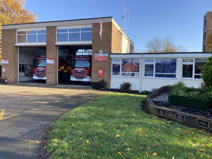 Brick fire station building with two bay doors and grass at the front