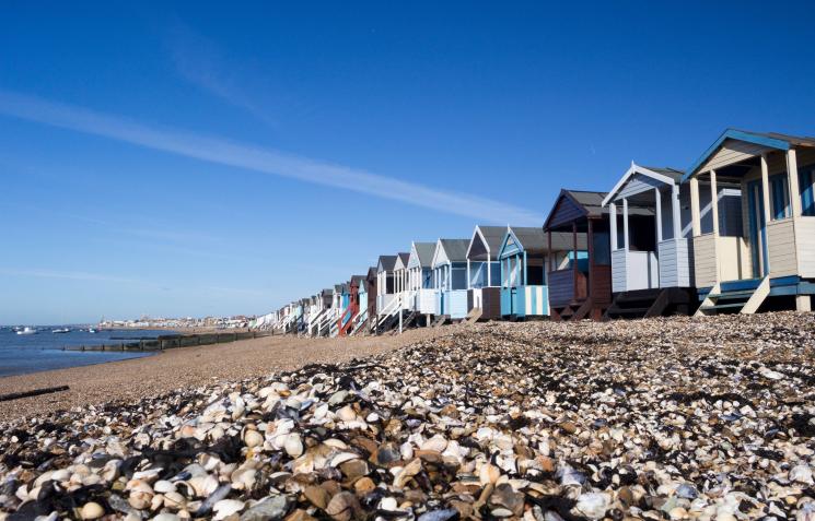 Series of blue-coloured beach huts on pebble beach in North Essex