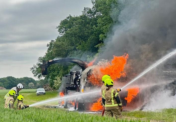 Firefighters spraying water on the woodpile and vehicles