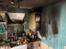The corner of a kitchen that has been blackened from smoke and fire damage. 