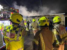 Three firefighters looking at a building which has smoke coming from it