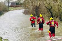 Four firefighters wading through floodwater