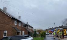 Firefighters outside a row of terraced houses, with smoke coming from the roof area