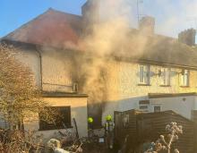 Two firefighters entering a terraced houses with smoke coming out