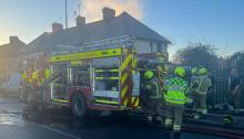 Firefighters and an appliance outside a row of terraced houses
