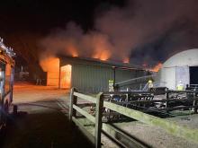 Barn on fire - two firefighters using hose to extinguish fire