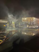 Firefighters spraying water at vehicles in a yard at night