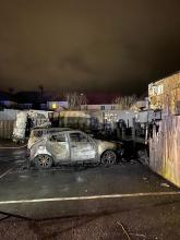 A burned out car in a yard at night