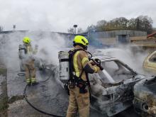 Firefighters extinguishing multiple cars on fir