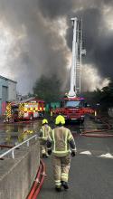Firefighters using an Aerial Ladder Platform to extinguish an industrial unit fire