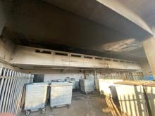 Large bins within an outside area. There is smoke damage above on the building.