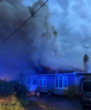 Smoke billowing out of the roof of a bungalow