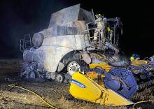 A firefighter on a burnt out combine harvester