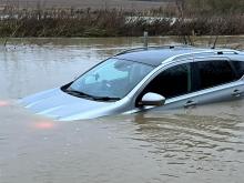 Firefighters walking through almost 4 ft of water to rescue a person trapped in their car