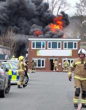 Firefighters at a two-storey building with fire and smoke coming from the roof