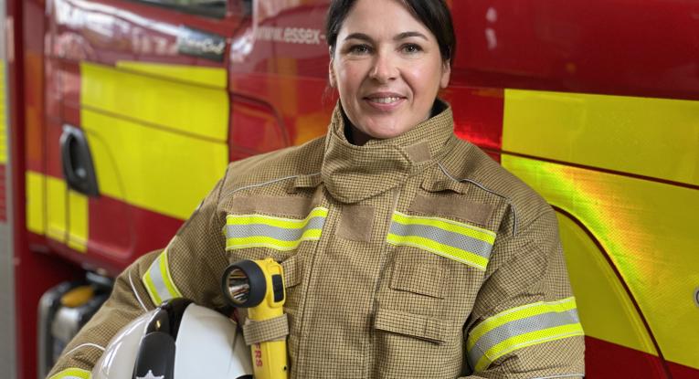 Our Deputy Chief Fire Officer Moira Bruin standing in front of a fire engine in her operational PPE. She is smiling.
