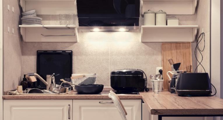 A kitchen with lots of mess on the work surfaces