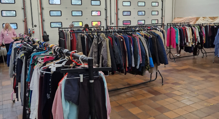 Clothes on racks at fire station being given away to people 
